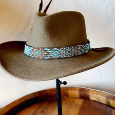 I wanted to create a turquoise rich band with traditional silver streak patterns throughout. This band is gorgeous on any hat color. It stands out and gets noticed!  I have spent hours creating this pattern. I love to incorporate a cross whenever possible. Time intensive, but worth it! Made with: *  6mm Kingman turquoise *  Miyuki glass beads *  Bronze aged oblong beads *  Silver arrow leather grips *  Sterling silver leather slide *  African silver rice beads *  Silver concho screw back w/turquoise center (concho = 35mm x 30mm *  Woven in 2mm turquoise *  Feather *  Leather and leather lace (soft, high quality) Width:  1 inch Length:  *Adjustable all western cowboy/cowgirl hats Beaded Hat Bands, Beaded Hat, Rice Bead, Kingman Turquoise, Cowgirl Hats, Leather Slides, Cowboy And Cowgirl, Western Cowboy, Hat Band