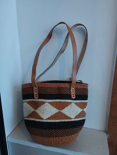 Geometrical earth tone sisal tote bag. Unique and stylish colorful sisal kiondo bag with stitched leather straps, pocket lining and zipper. Patterns and sizes slightly vary because weaving and stiching is done by hand. Ideal as a beach bag, shopping basket, market basket or storage basket. This unique tote bag is handmade by a group of ladies in a remote rural village in Machakos, Kenya. Do not clean with brush or water. If the bag gets wet, please dry to avoid dampness.  Leather type used is bo Brown Woven Shoulder Bag For Everyday, Black Large Capacity Shoulder Bag For Market, Daily Use Woven Tote Shoulder Bag, Brown Basket Shoulder Bag With Adjustable Strap, Brown Woven Satchel For Everyday Use, Large Capacity Brown Crochet Handheld Bag, Brown Handheld Crochet Bag With Large Capacity, Brown Large Capacity Handheld Crochet Bag, Everyday Brown Woven Satchel