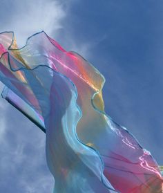 a colorful kite flying in the sky on a sunny day with blue skies and white clouds