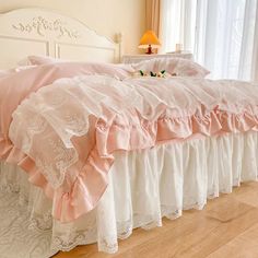 a bed with pink and white ruffled bedspread on it's headboard