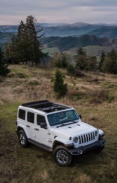 a white jeep parked on top of a grass covered field