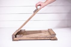 a person holding a knife over a wooden cutting board on top of a white table