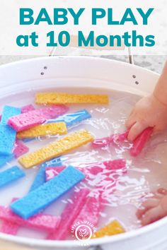 baby play at 10 months in a tub with pink, blue and yellow sponges