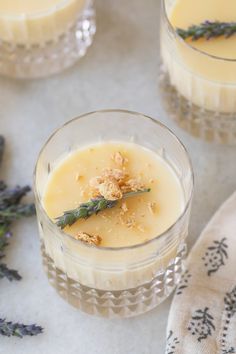 two glasses filled with pudding sitting on top of a table next to some lavender flowers