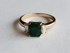 Beautiful dark green natural swat valley emerald with natural baguette diamonds. This 3 stone ring is simple but very elegant.       Natural emerald 2.5 carat      Natural diamonds VSI .2 tcw     14k solid gold     NOTE: Emerald color, weight and dimensions may vary from listing above, will notify customer and send up to date imaging of emeralds available. Diamond weight is approximate. -  Made to order -Please allow 2-4 weeks after purchase for shipping - -  Emerald can be GIA certified for an additional $80 - - 30 day return permitted and refund completed upon inspection - Gold And Emerald Ring Engagement, Dark Emerald Green Ring, Emerald Stone Engagement Ring Vintage, Emerald Green Engagement Ring Vintage, Dark Emerald Engagement Ring, Dark Green Ring, Non Traditional Engagement Rings Vintage, Emerald And Diamond Engagement Ring, Unique Engagement Rings Emerald