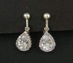 Pair of clear and silver clip on earrings feature a larger CZ teardrop in the center surrounded by smaller round CZ's. Set in a silver plated frame.  Earrings are 7/8 inches (2.2cm) long. Silver plated clip on earring tops with screw back and comfort cushion. Find more clip on earrings here - https://www.etsy.com/shop/BeautifulByCharlene?section_id=11497371 Earring Tops, Frame Earrings, December Birthday Gifts, Clip On Earring, Blue Topaz Necklace, Earrings Teardrop, Blue Zircon, Silver Rhinestone, Silver Filigree