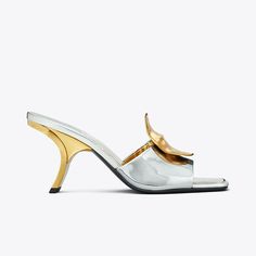 Our Patos sandal is defined by mismatched metal discs, evocative of ’60s glamour. Crafted in metallic leather, the sculptural silhouette features a slanted heel that gives it a chic, distorted look. A cushioned insole ensures day-to-night comfort. Modern Pointed Toe Cocktail Sandals, Modern Open Heel Sandals For Cocktail, Luxury Silver Mules With Sculpted Heel, Luxury Silver Mules For Party, Luxury Silver Mules With Padded Heel, Modern Sandals With Single Toe Strap For Cocktail, Glamorous Leather Mules With Sculpted Heel, Modern Cocktail Sandals With Single Toe Strap, Modern Gold Heels With Sculpted Heel