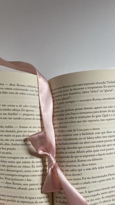 an open book with a pink ribbon on the cover and pages in spanish are shown