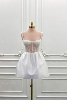 a short white dress on a mannequin stand in front of a white wall