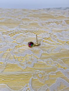 a pair of earrings sitting on top of a yellow lace