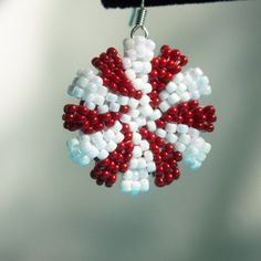 a red, white and blue beaded snowflake ornament hanging from a hook