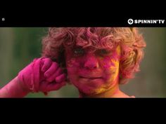 a young boy covered in colored powder holding his hand to his ear