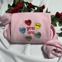 a pink purse with hearts and the words you are surrounded by red roses on a white sheet