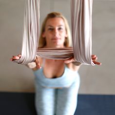 a woman is doing exercises on a hammock in front of the camera with her hands