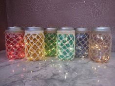 four jars with lights in them sitting on a counter top next to each other,