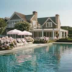 a large house with a pool in front of it and flowers on the lawn next to it