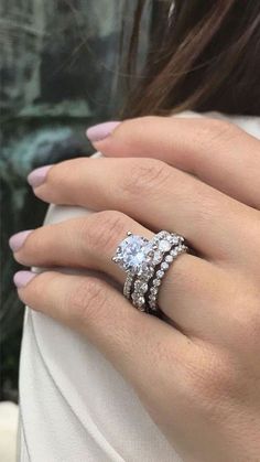 a woman's hand with three diamond rings on her left and the other hand holding an engagement ring