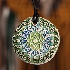 The Armenian region showcases the harmonious beauty of its classic artistry in this gorgeous necklace by Arpine Matevosyan. The artisan uses her refined talent in this accessory, decorated with a round pendant of floral and leafy allure. Painted by hand in green and blue hues, the design comes with a comfortable cotton cord. Green Hand Painted Spiritual Jewelry, Hand Painted Green Spiritual Jewelry, Spiritual Hand Painted Green Jewelry, Traditional Hand Painted Adjustable Necklace, Traditional Adjustable Hand Painted Necklace, Artistic Round Pendant Necklaces For Art Collection, Elegant Necklace With Artistic Round Pendant, Artisan Hand Painted Blue Necklace, Artisan Pendant Jewelry With Decorative Details