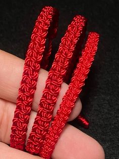 three pieces of red rope sitting on top of each other in someone's hand