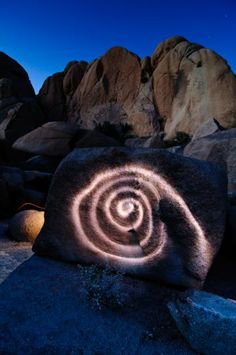 a rock with an image of a spiral on it in the middle of some rocks