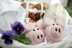 three pigs are sitting in a basket next to some bundt cakes and purple flowers