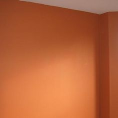 an empty bedroom with orange walls and white bedding