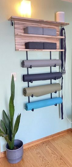 a wall mounted shelf with yoga mats and a potted plant