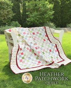 a white bench sitting in the grass with a quilt on it's back end