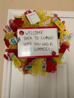 a welcome back to class wreath is hanging on the front door with some school supplies