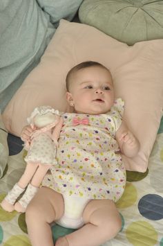 a baby laying on top of a bed holding a stuffed animal