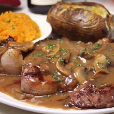 a white plate topped with meat covered in mushroom gravy and mashed potatoes