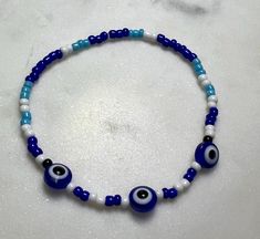 Beaded evil eye bracelet. Blue and white. Adjustable Blue Evil Eye Bracelet Hand-strung, Handmade Blue Evil Eye Bracelet For Festival, Adjustable Blue Hand-strung Evil Eye Bracelet, Handmade Bohemian Blue Evil Eye Bracelet, Handmade Blue Bohemian Evil Eye Bracelet, Handmade Blue Stretch Bracelet For Festivals, Spiritual Blue Stretch Bracelet With Letter Beads, Blue Spacer Beads Bracelets For Festivals, Blue Festival Bracelets With Spacer Beads