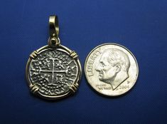 a coin with a cross on it next to a pendant