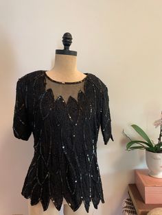 "Gorgeous & detailed black 70's/80's sequin & beaded top. 100% silk. Made in India. Feather/ leaf scallop design that continues through to the edge of the sleeves and bottom hem. Beautiful black silk sheer neckline with beaded edge. Closure is a little hook & eye as well as a zipper that goes almost to the bottom, for ease in getting it on and off.  The beading and sequins work are so beautiful. Comes with shoulder pads, but they could easily be removed if thats not your look.  Would be perfect as evening party dress top, or with jeans and heels I would say this is a Medium, based on fit, but could easily work a bit smaller or bigger, based on measurements.  measurements (taken when lying flat, double for estimated sizing) armpit to armpit  20\" waist at smallest part  18\" bottom hem  21\ Fitted Black Sequin Fabric For Cocktail, Fitted Black Sequin Fabric For Summer, Elegant Sequin Fabric For Evening In Summer, Elegant Summer Evening Sequin Fabric, Black Fitted Sequin Fabric For Holiday, Fitted Embellished Sequin Dress With Short Sleeves, Fitted Short Sleeve Embellished Sequin Dress, Elegant Black Sequin Fabric For Summer, Elegant Fitted Sequin Top