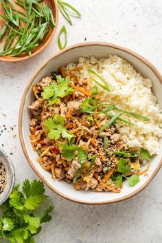 a bowl filled with rice, meat and cilantro on top of a table