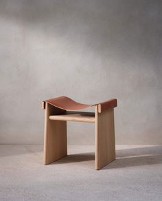 a small wooden bench sitting on top of a white floor next to a gray wall