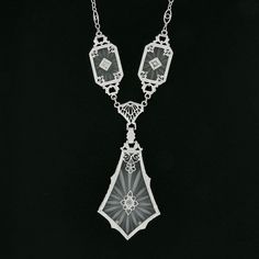 "This is a magnificent antique pendant necklace that was crafted during the art deco period in solid 14k white gold. It features three camphor glass panels with the largest dangling at the center, and each is set with a fine old single cut diamond that adds a lovely touch of sparkle to this piece. The camphor glass displays magnificent etching designs and is elegantly bezel set and framed with etched patterns throughout and further adorned with lovely floral filigree work. The largest camphor gl Luxury Art Deco Necklace With Polished Finish, Art Deco Platinum Jewelry For Evening, Victorian White Gold Pendant Necklace, Antique White Gold Pendant Necklace, Victorian White Gold Medallion Necklace, Antique White Gold Necklace With Intricate Design, Victorian White Gold Necklace For Anniversary, White Gold Victorian Necklace For Anniversary, Victorian Style White Gold Necklace For Anniversary