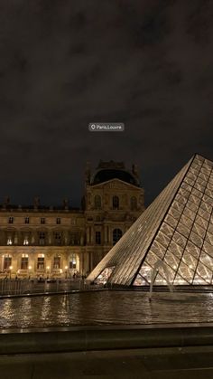 the pyramid is lit up at night in front of an old building