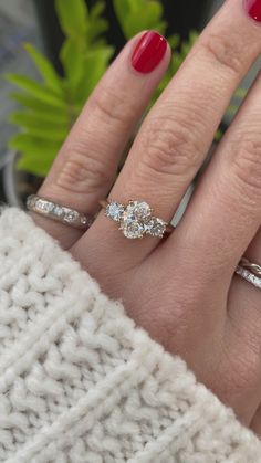 a woman's hand with three rings on it and a plant in the background