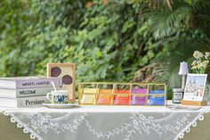 a table topped with books and cards on top of a white table cloth next to trees