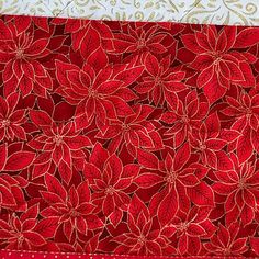 a red and white quilted table runner with poinsettia flowers on it