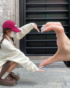 a woman kneeling on the ground with her hand extended out to touch another person's finger