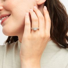 a woman wearing a diamond ring on her left hand and holding it up to her right ear