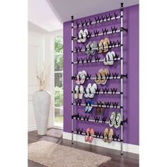 a wall mounted shoe rack with multiple pairs of shoes on it in front of a purple wall