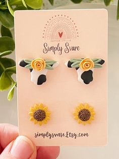 the sunflower earrings are on display in front of a plant