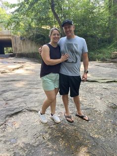 a man and woman standing on top of a rock