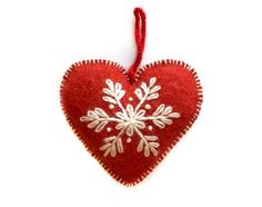 a red heart ornament with white snowflakes hanging from it's side