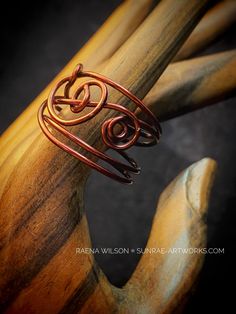 a close up of a wooden object with metal wire on it's end and an open spiral design in the middle