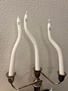 three white candles sitting on top of a metal candelabra next to each other