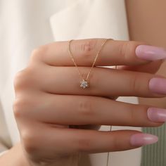 a woman's hand wearing a gold ring with a small diamond on the middle